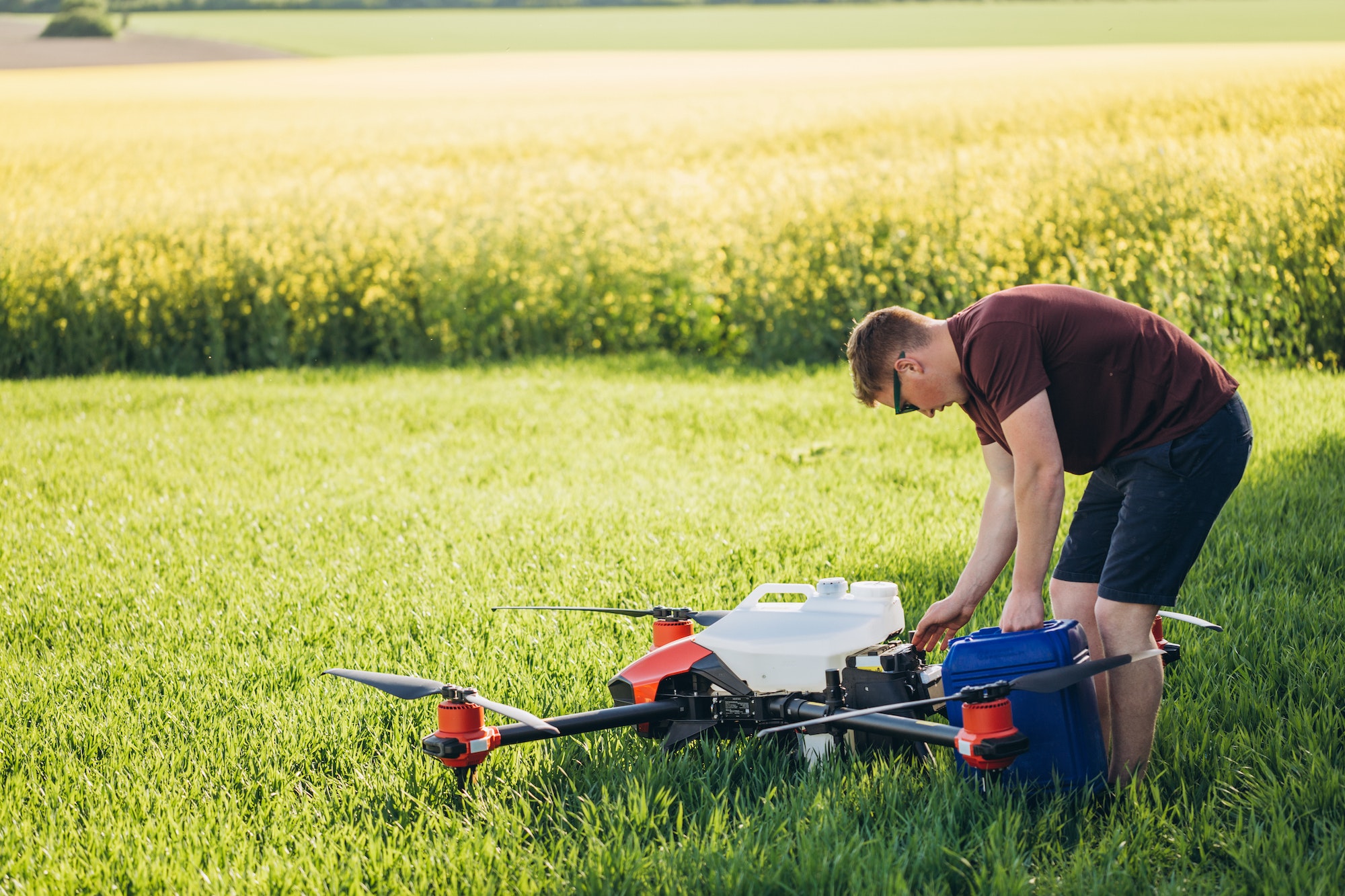 Attractive farmer navigating drone above farmland. High technology innovations